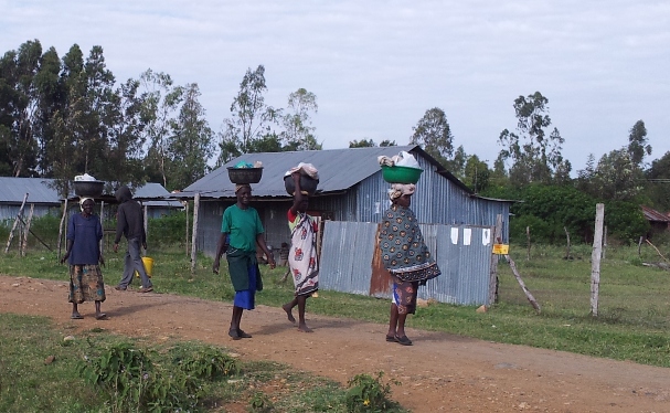 Village women walk with baskets balanced on their heads.